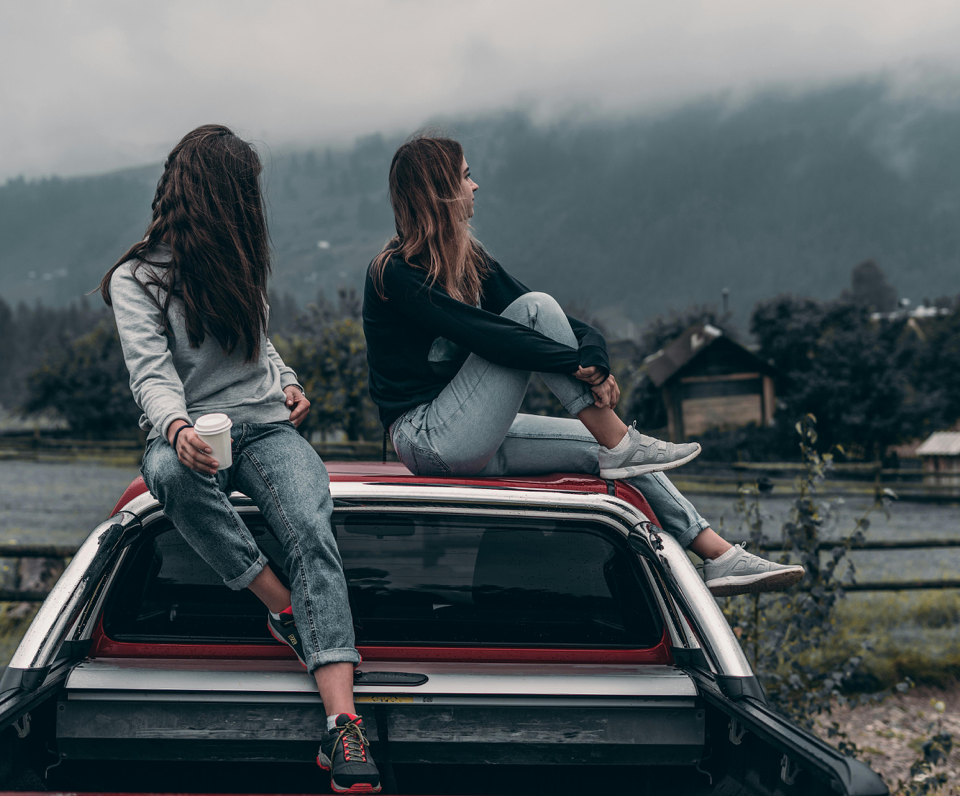 Two Women Sitting on Vehicle Roofs