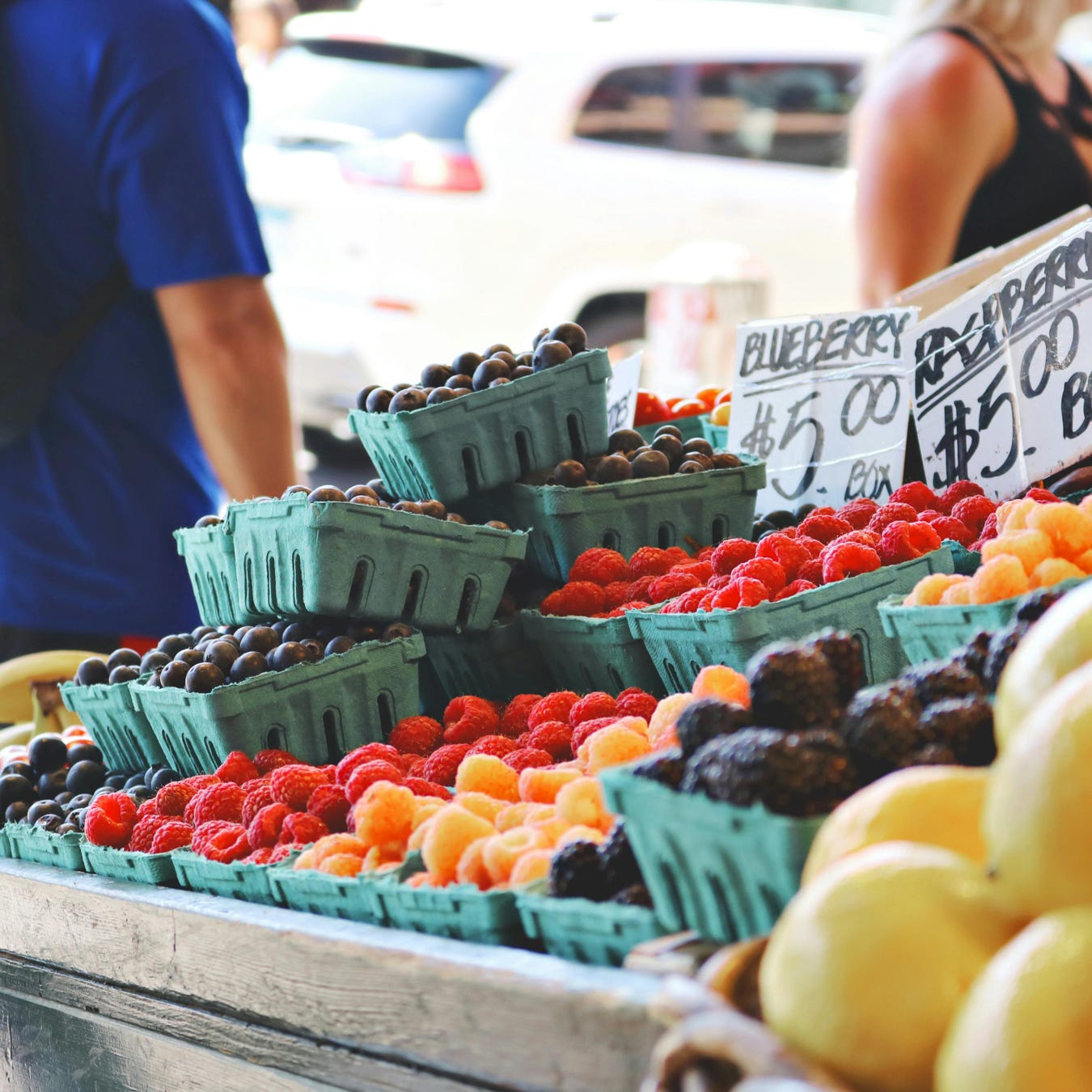 Man Wearing Blue Top and Black Bottom Standing Near Fruit Stand